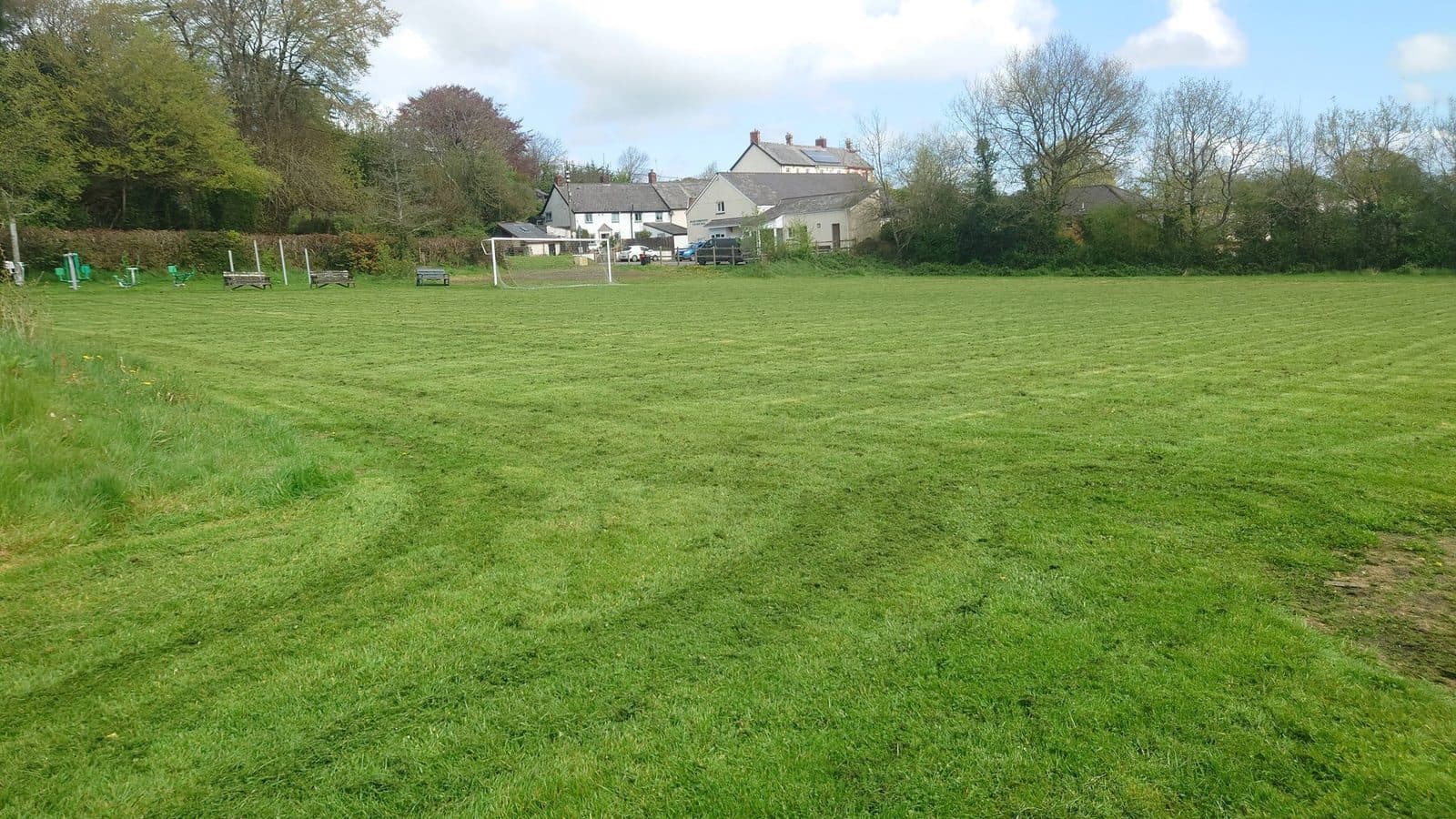 Large striped mown field with farmhouse in the distance