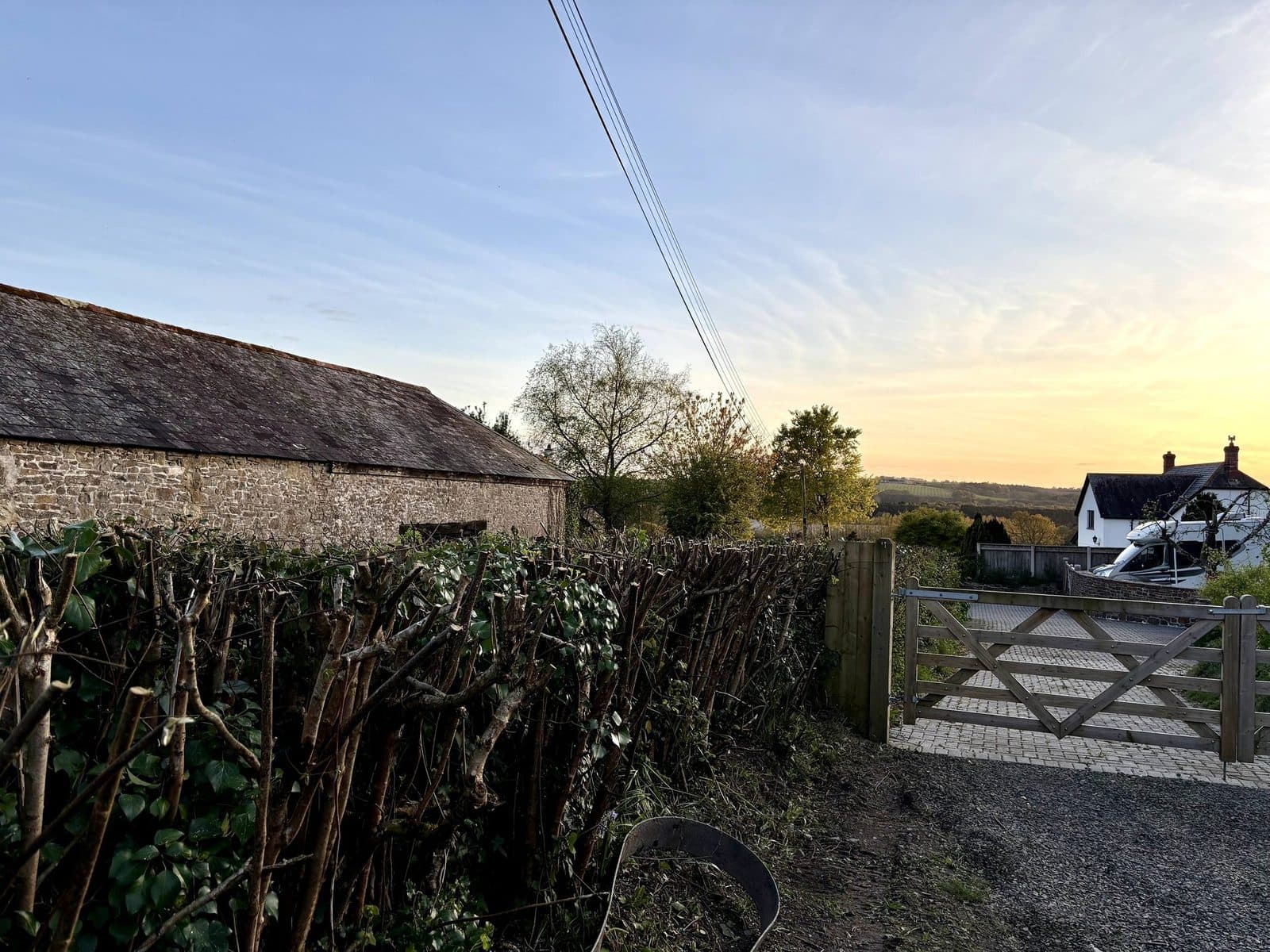 Devon cottage with 5-bar gate and freshly cut hedge — golden-hour rural scene